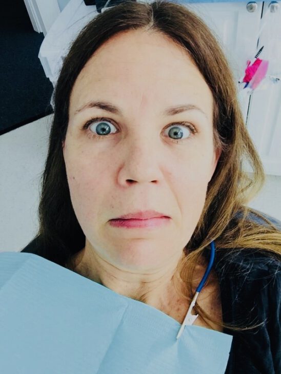 deaf at the dentist. woman looking scared wearing a dental bib