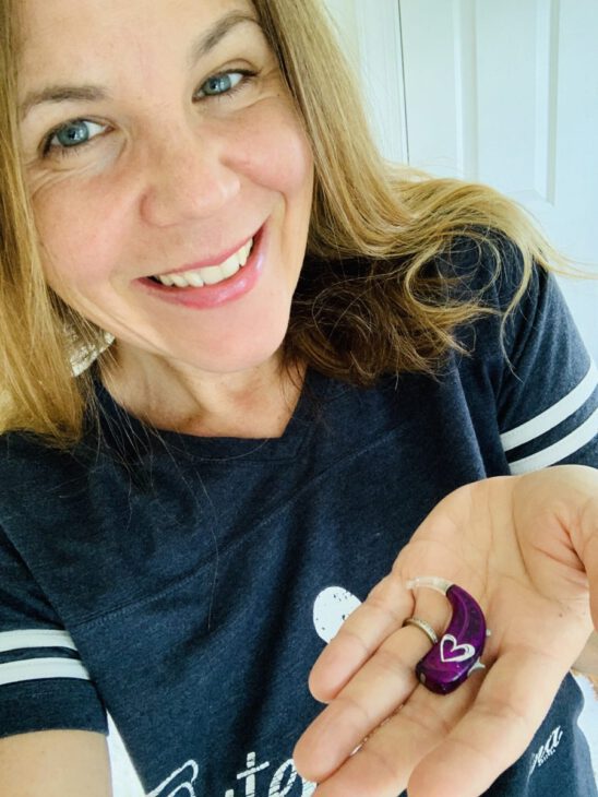 woman holds up a purple hearing aid up to the camera - what to expect from hearing aids