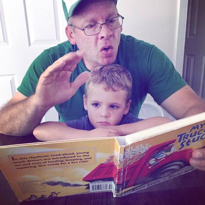 a young KODA is being read to in ASL by his Deaf dad